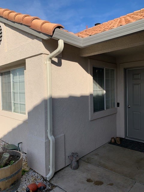 Clean gutter line installed under a tile roof on a stucco home